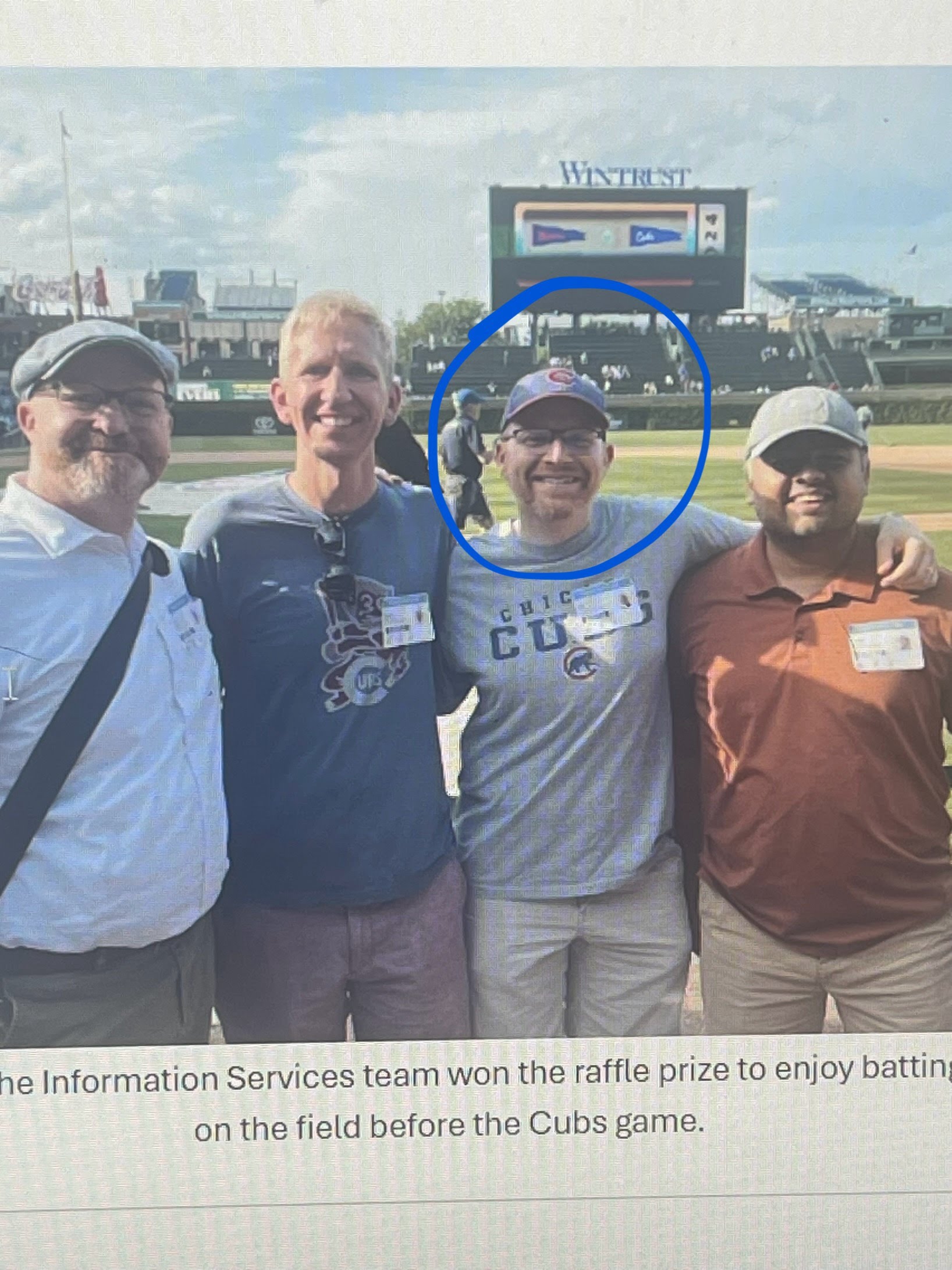 four people at a baseball game, guy with hat and glasses circled in blue